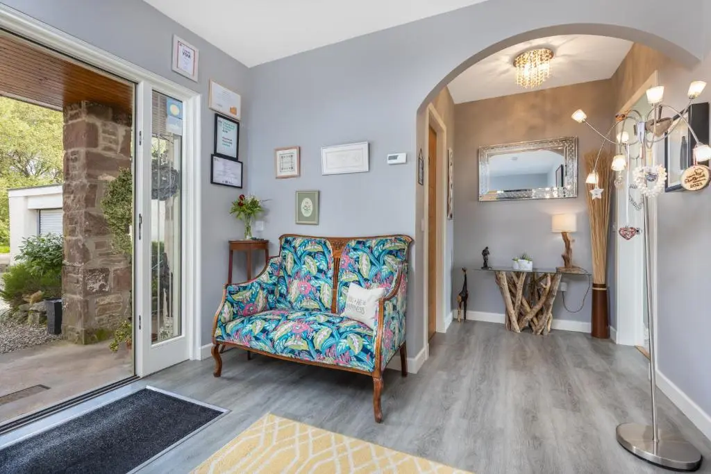 a living room with a chair and a mirror at Heartseed House Bed & Breakfast in Dornoch