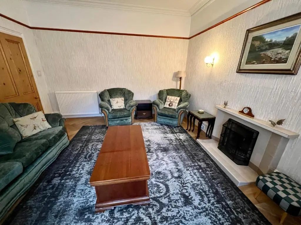 a living room with couches and a table and a fireplace at Convalmore House in Dufftown