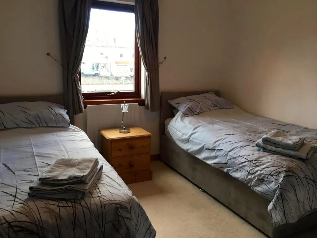 a bedroom with two twin beds and a window at 3 Marina Quay in Lossiemouth