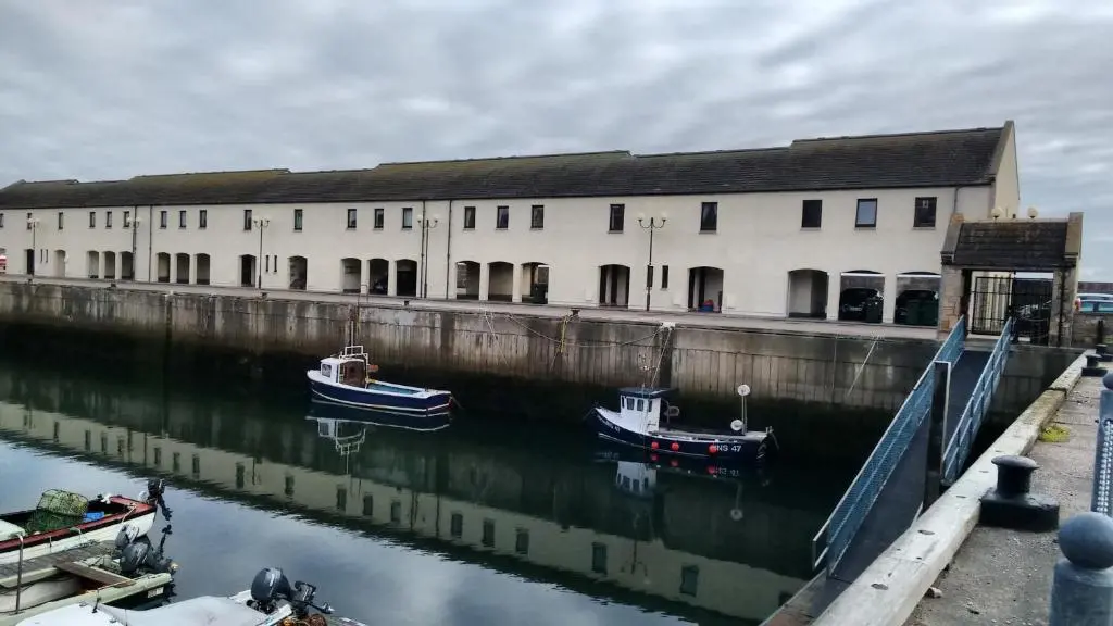 two boats are docked in the water in front of a building at 3 Marina Quay in Lossiemouth