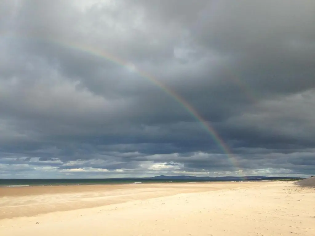 a rainbow on a beach under a cloudy sky at 3 Marina Quay in Lossiemouth