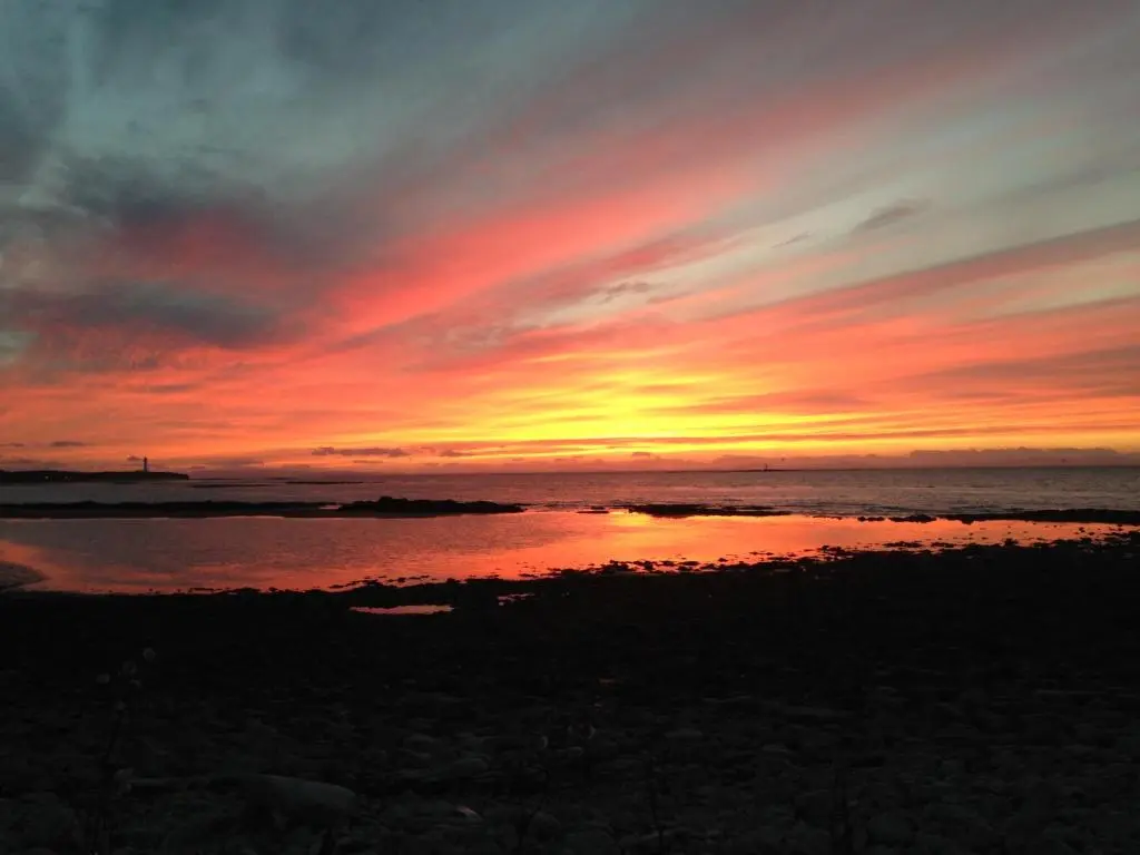 a sunset on the beach with the ocean at 3 Marina Quay in Lossiemouth