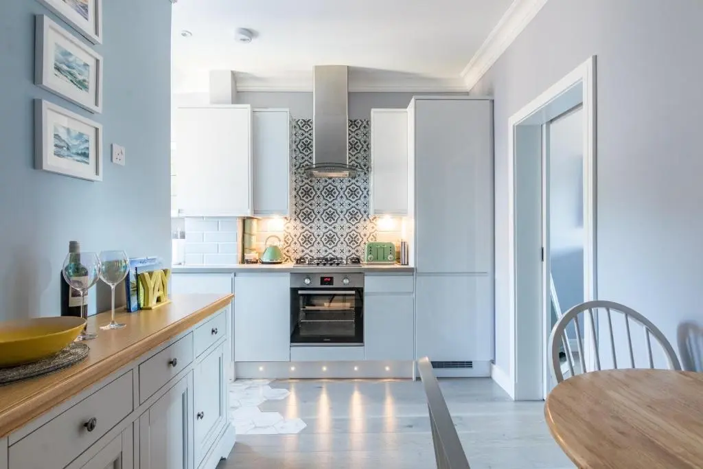 a kitchen with white cabinets and a table with a dining room at BlueNess in Inverness