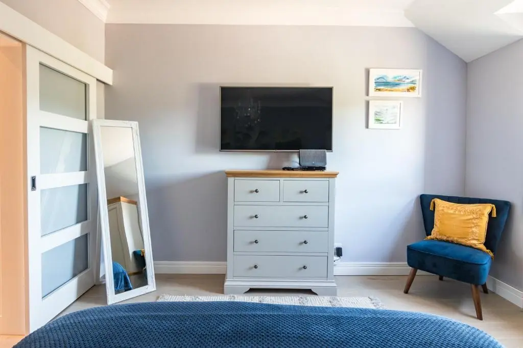 a bedroom with a television and a dresser with a mirror at BlueNess in Inverness