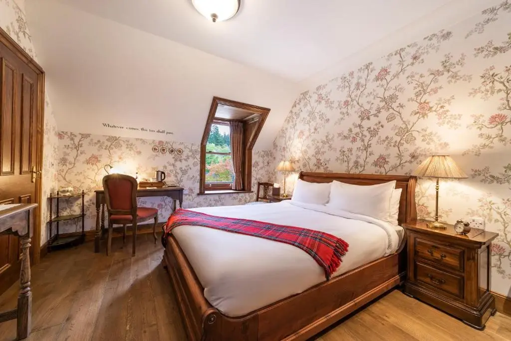 a bedroom with a bed and a desk and a chair at Rokeby Manor in Invergarry