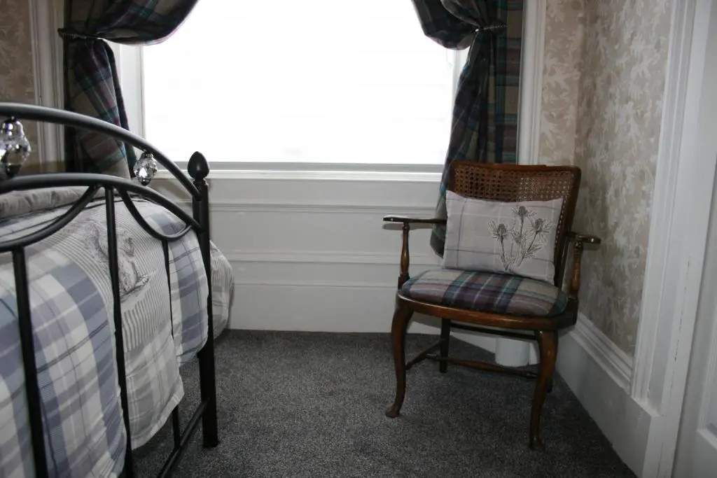 a chair sitting in front of a window in a bedroom at Ardmeanach in Inverness