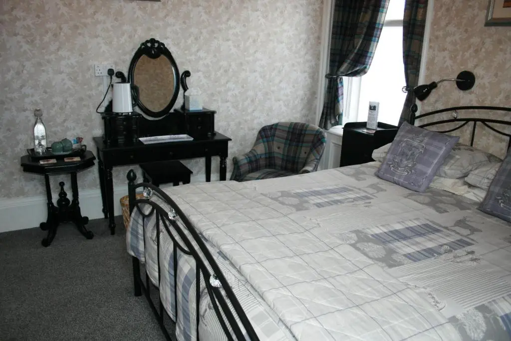 a bedroom with a bed with a mirror and a chair at Ardmeanach in Inverness