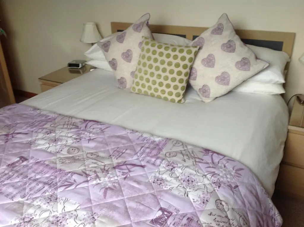a bed with a purple and white comforter and pillows at Dunroamin Bed and Breakfast in Aviemore
