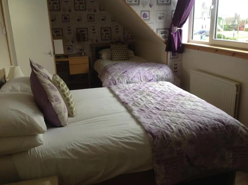 a bedroom with two beds with purple blankets at Dunroamin Bed and Breakfast in Aviemore