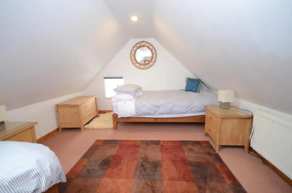a attic bedroom with a bed and a mirror at Driftwood Cottage, Portsoy in Banff