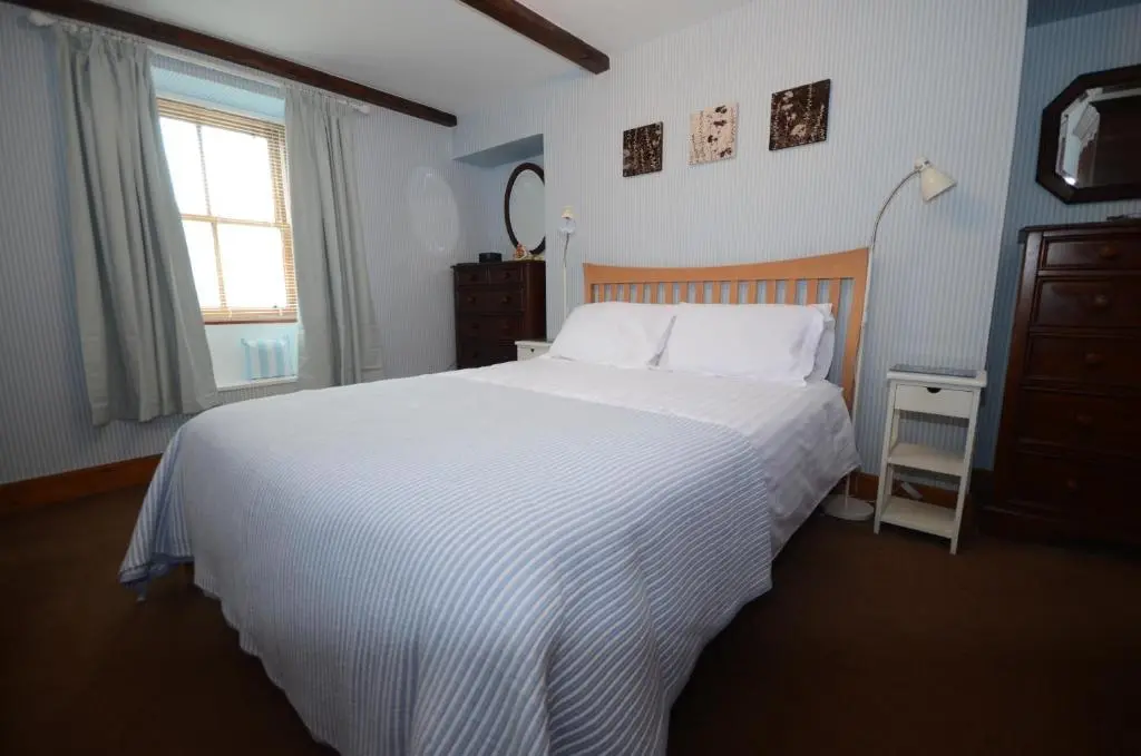 a bedroom with a large white bed and a window at Driftwood Cottage, Portsoy in Banff