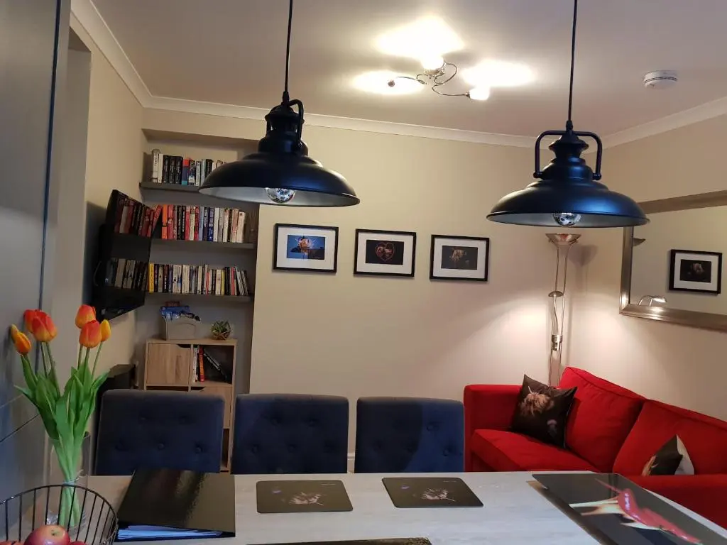 a living room with two lights hanging over a table at Smart & Cozy Holiday Apartment in the city centre in Inverness