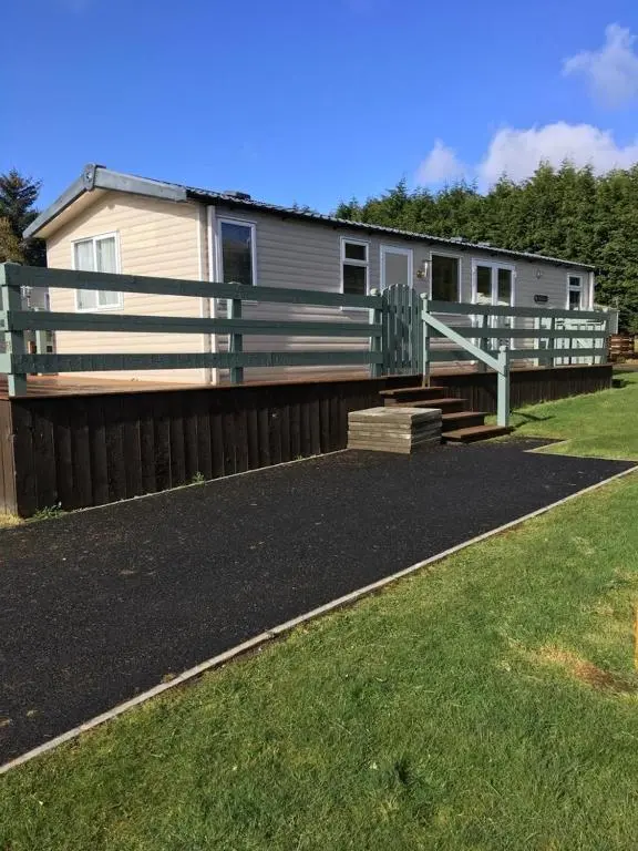 a mobile home with a fence and a yard at Braemar in Dornoch
