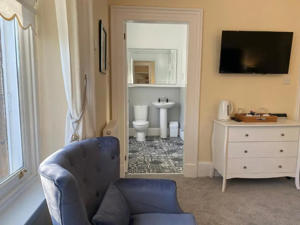 a living room with a blue chair and a bathroom at Ardross Glencairn in Inverness