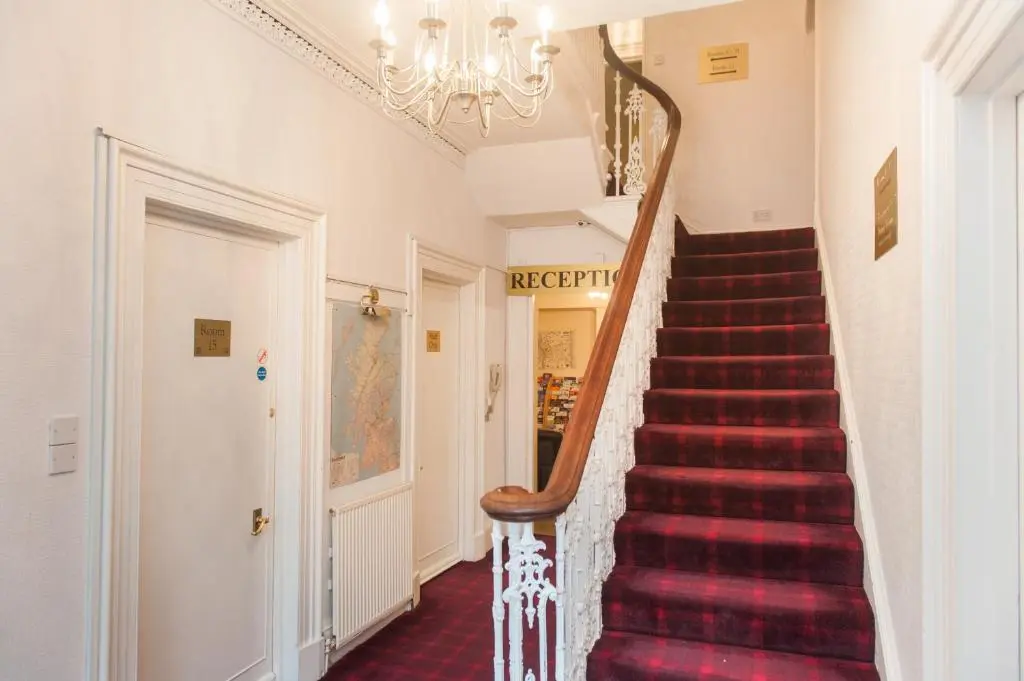 a staircase with red carpeting and a chandelier at Ardross Glencairn in Inverness