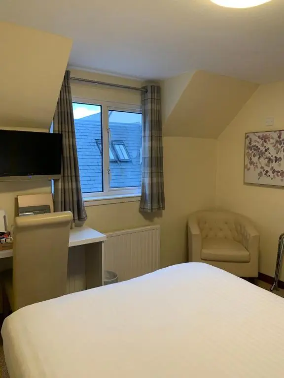 a bedroom with a bed and a chair and a window at Ardross Glencairn in Inverness
