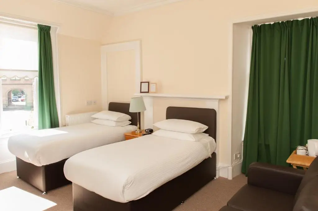 two beds in a room with green curtains at Ardross Glencairn in Inverness