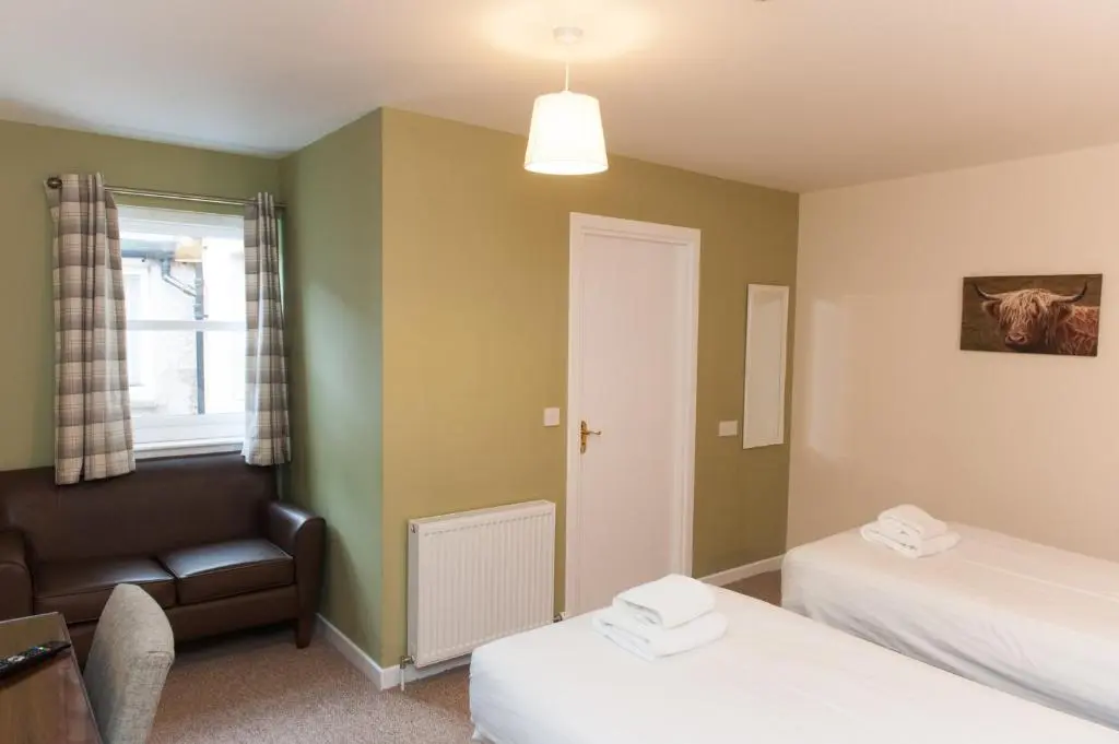 a room with two beds and a couch and a chair at Ardross Glencairn in Inverness