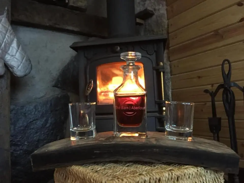 a bottle of whiskey on a table with two glasses at The Barn | Aberlour in Aberlour