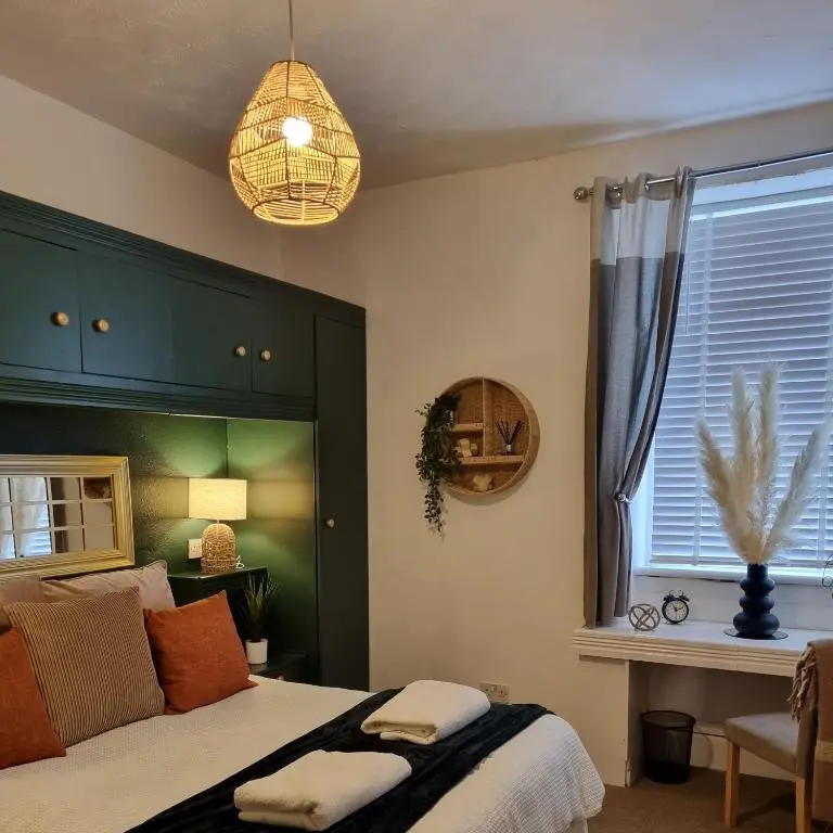 a bedroom with a bed with a green headboard and a window at Inverness City Centre Flat in Inverness