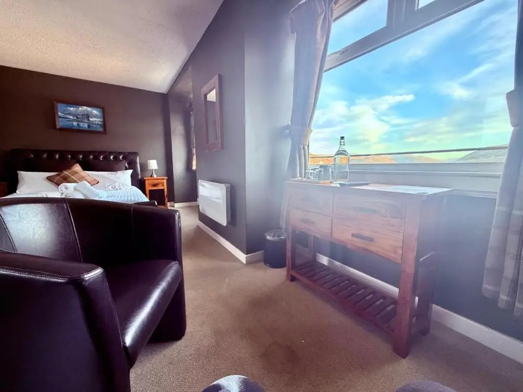 a bedroom with a bed and a sink and a window at Argyll Hotel in Ullapool