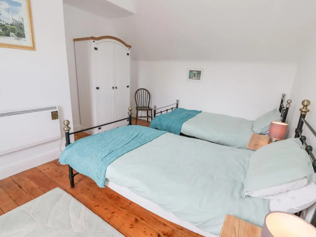 a bedroom with two beds and a chair at Church View in Kingussie
