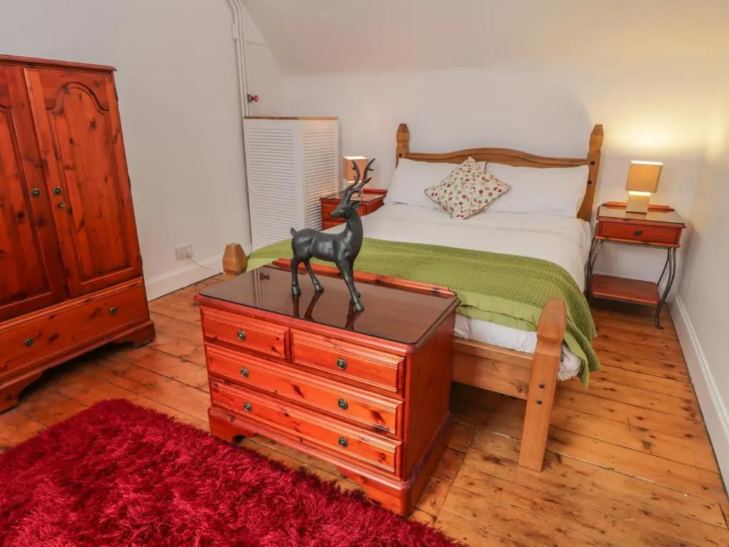a bedroom with a bed and a dresser with a statue on it at Church View in Kingussie