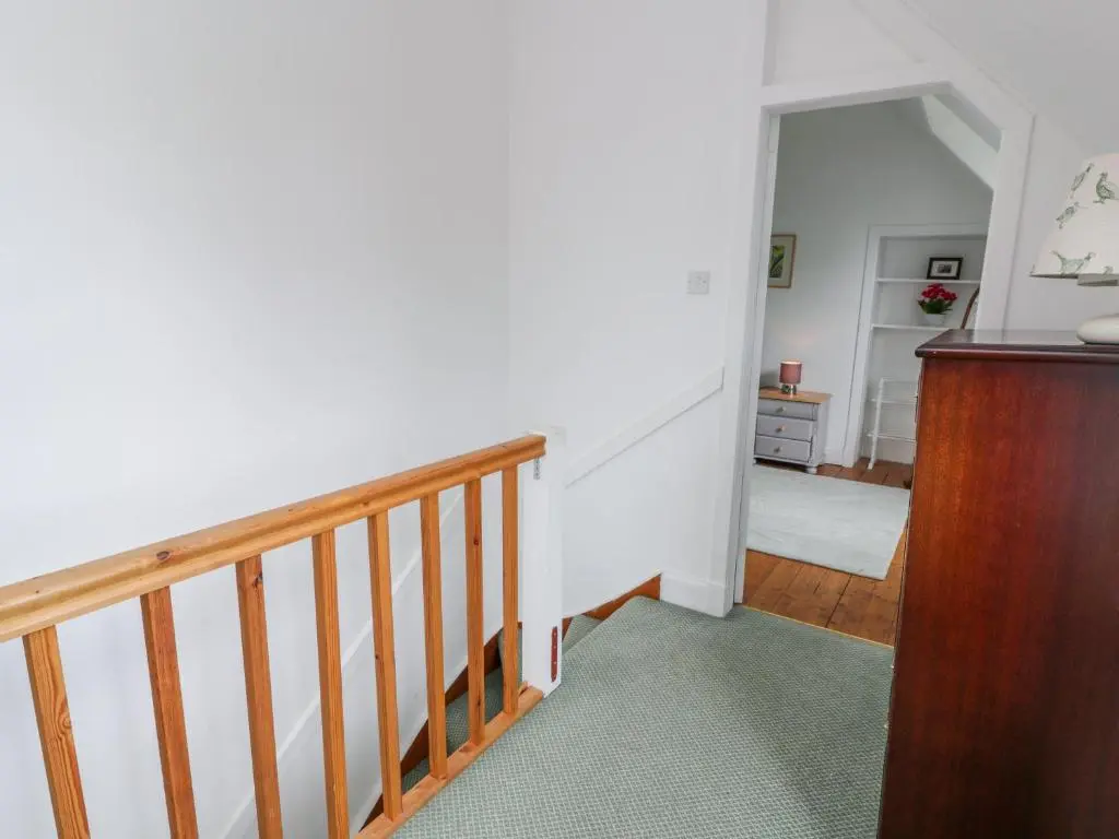 a hallway with a stairway with a wooden rail at Church View in Kingussie