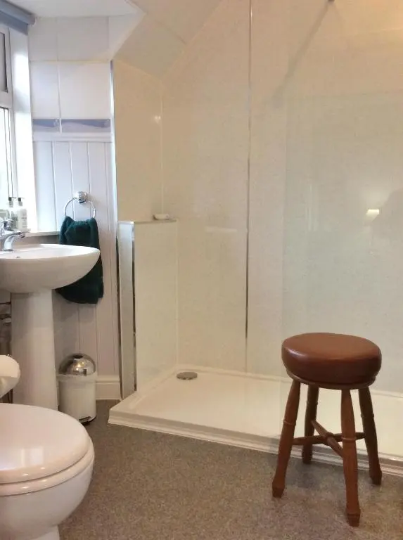 a bathroom with a toilet and a stool next to a shower at Clune House B&B in Newtonmore