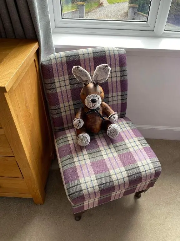 a teddy bear sitting on a plaid chair at Clune House B&B in Newtonmore