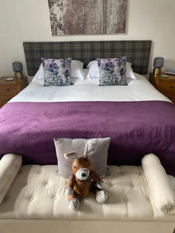 a stuffed animal is sitting on a bed at Clune House B&B in Newtonmore