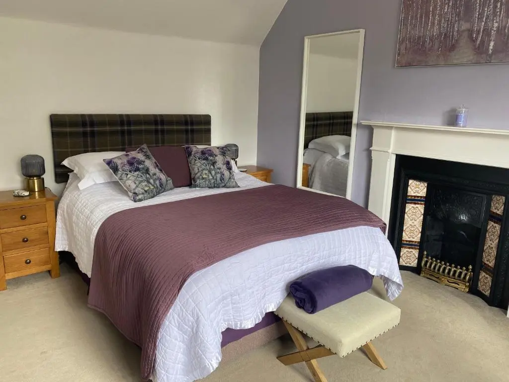 a bedroom with a large bed and a fireplace at Clune House B&B in Newtonmore