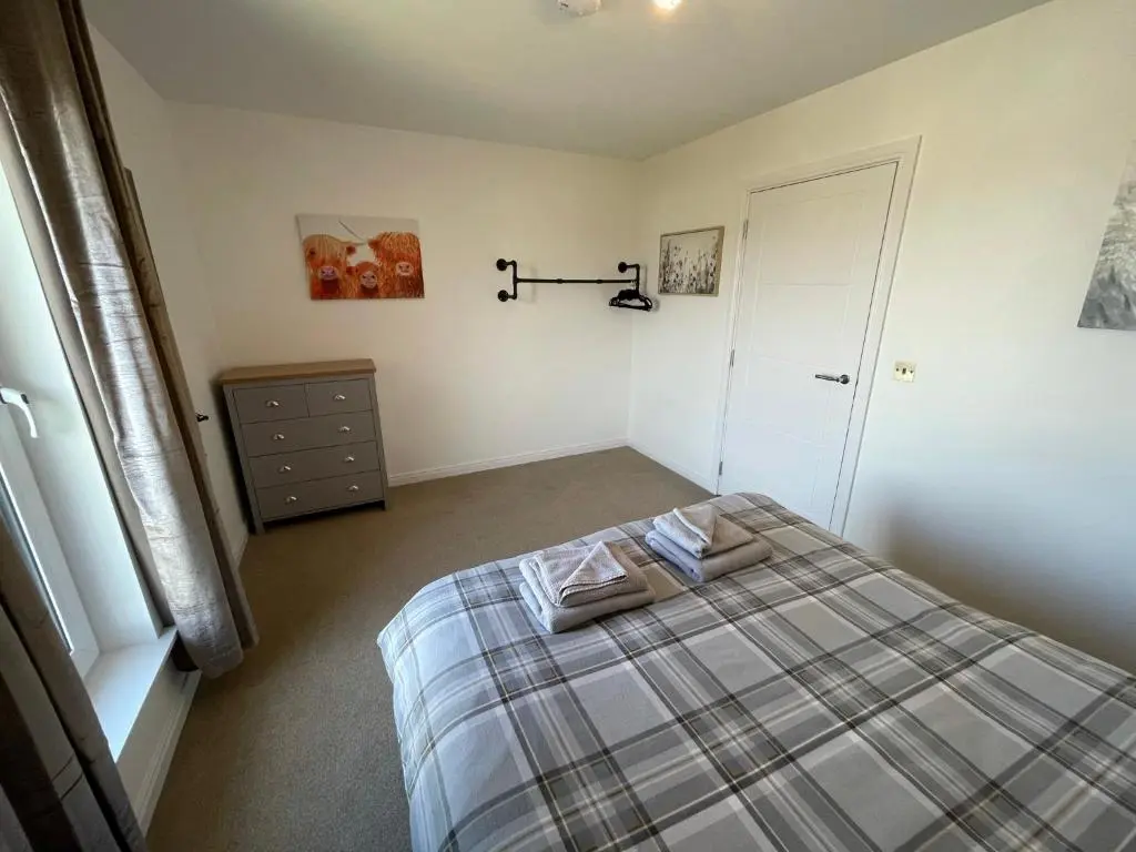 a bedroom with a bed with a plaid blanket at Gorsebank View in Inverness