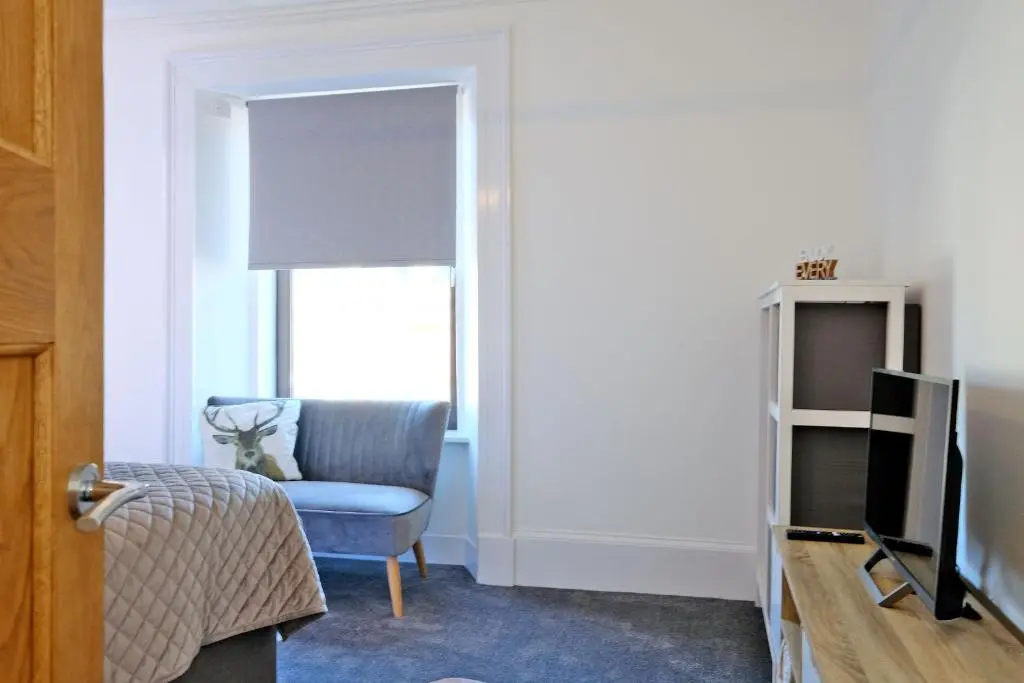 a living room with a blue chair and a television at Ben Shea Smart Home in Dufftown