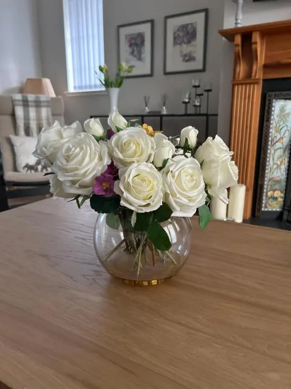 a vase filled with white roses on a table at The Maples 26 Wellingtonia Court in Inverness