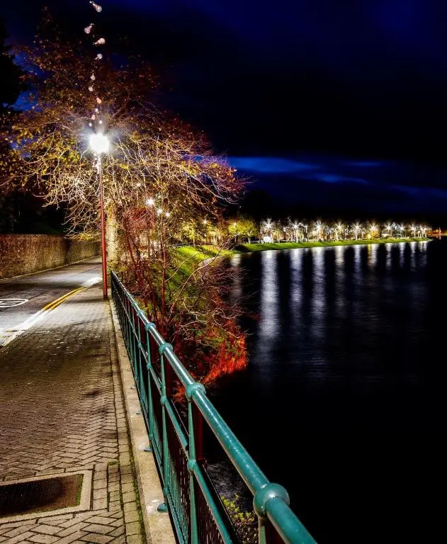 a street light next to a body of water at night at The Maples 26 Wellingtonia Court in Inverness