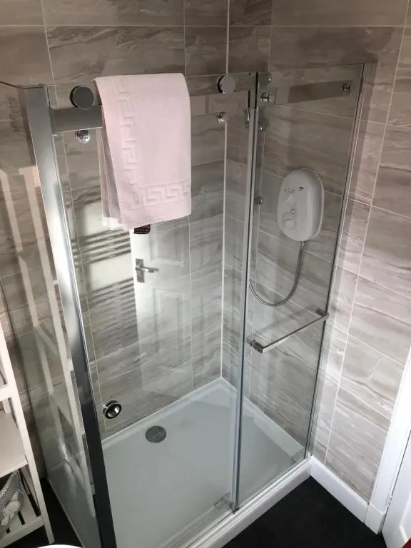 a shower with a glass door in a bathroom at L&H APARTMENTS in Inverness