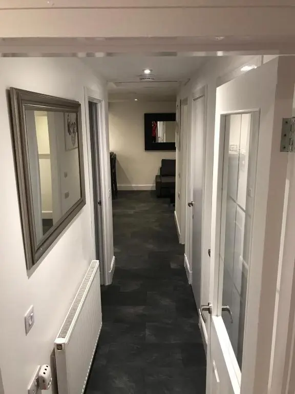 a hallway leading to a living room with a mirror at L&H APARTMENTS in Inverness