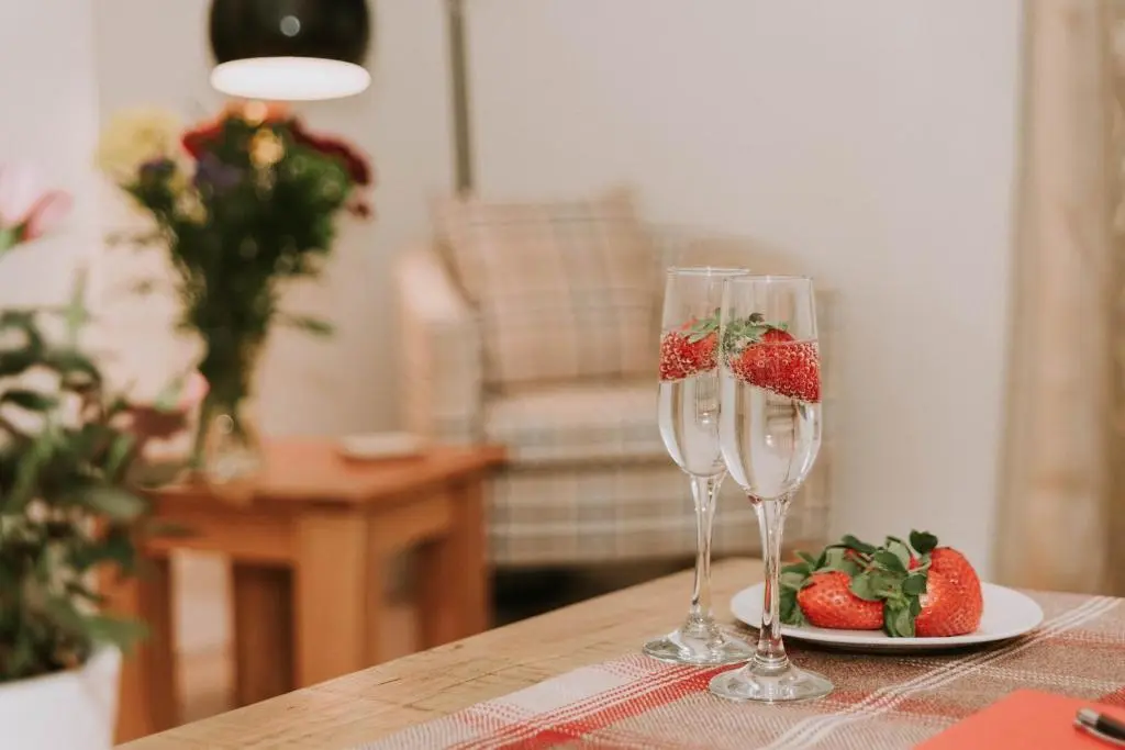two wine glasses sitting on a table with a plate of strawberries at The King Street Holiday Apartment in Inverness City Centre in Inverness
