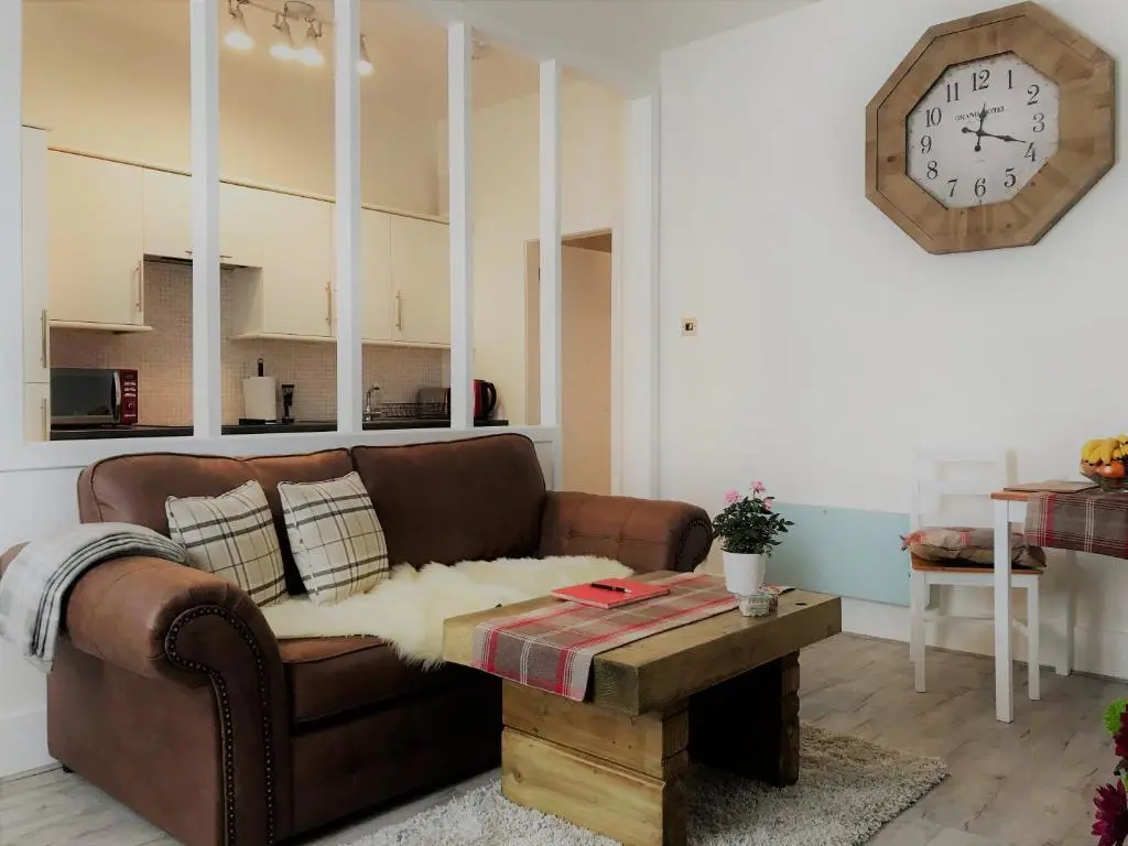a living room with a couch and a clock on the wall at The King Street Holiday Apartment in Inverness City Centre in Inverness