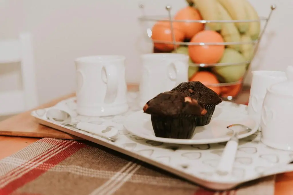 a chocolate muffin on a plate on a table at The King Street Holiday Apartment in Inverness City Centre in Inverness
