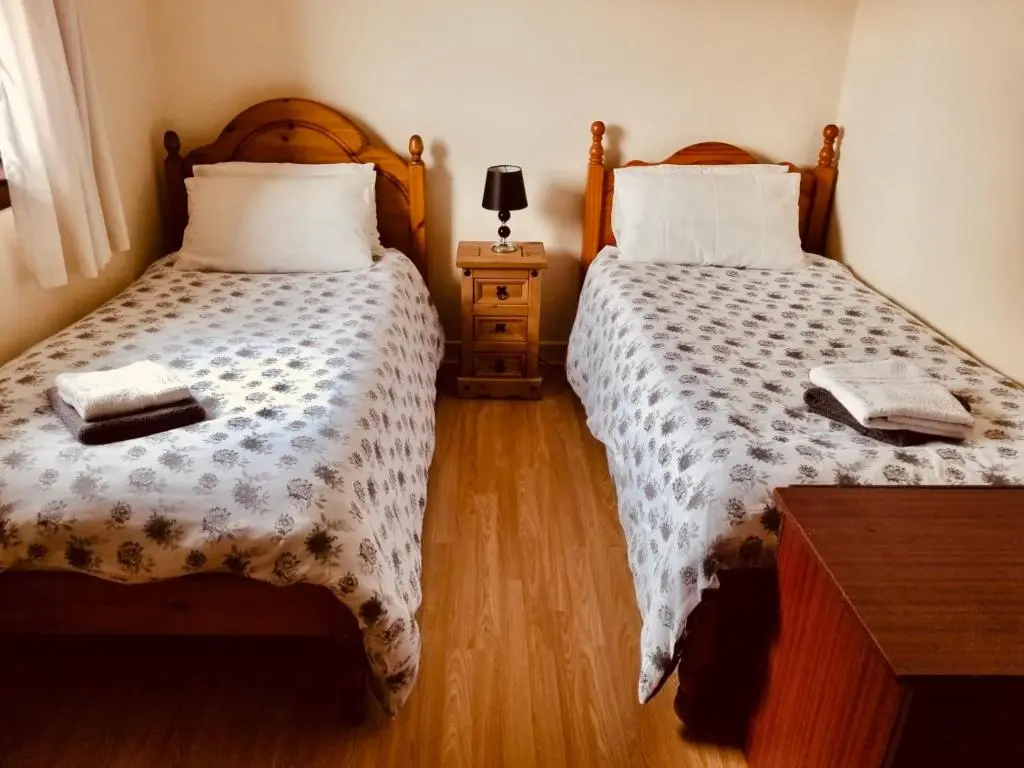 a bedroom with two beds and a table with a lamp at Inverken House in Inverness