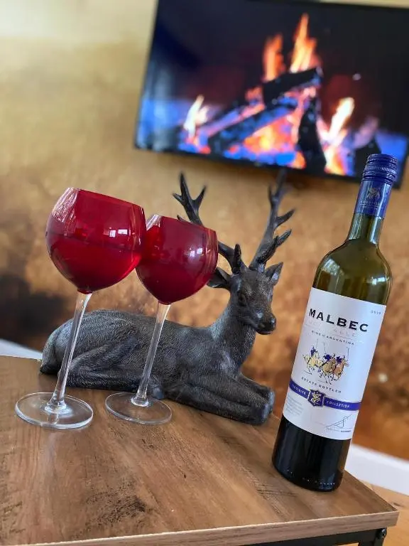 a bottle of wine and two wine glasses on a table at Druid House Lodge in Inverness