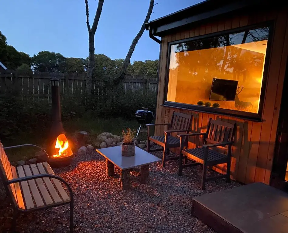 a patio with two chairs and a table and a fireplace at Druid House Lodge in Inverness
