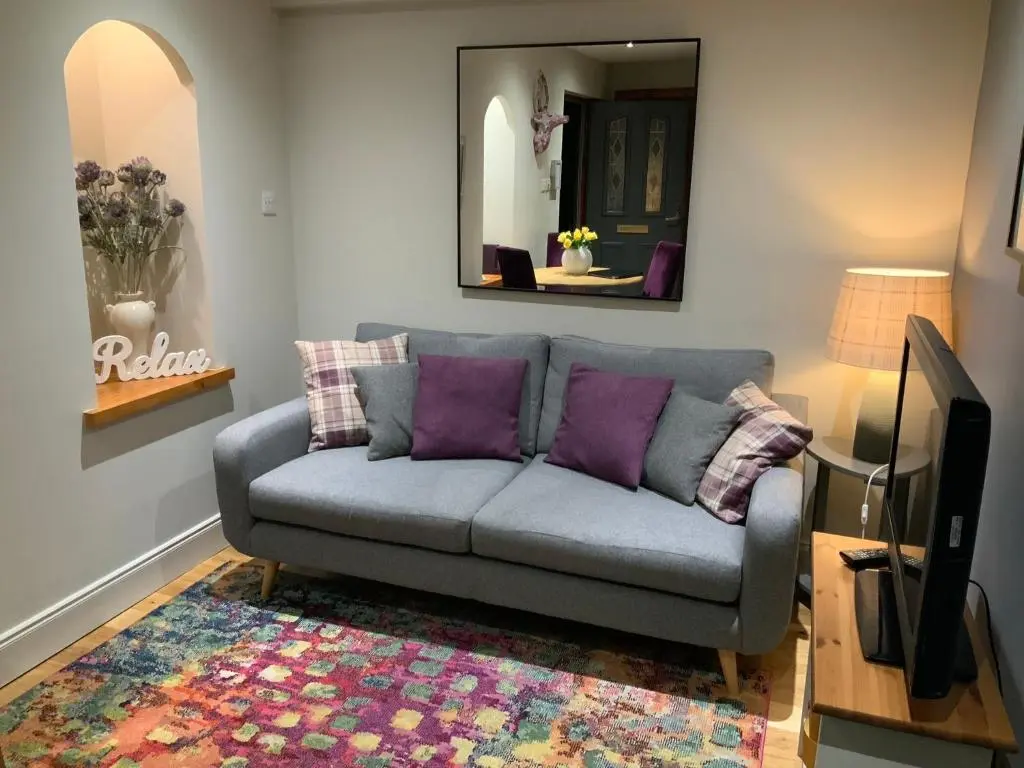 a living room with a couch and a mirror at Corran Cottage in Inverness