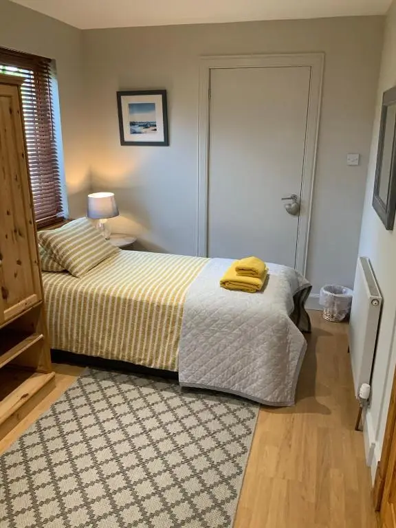 a bedroom with a bed with a yellow towel on it at Corran Cottage in Inverness