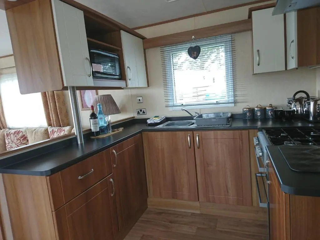 a kitchen with wooden cabinets and black counter tops at No42 Wild Goose in Dornoch