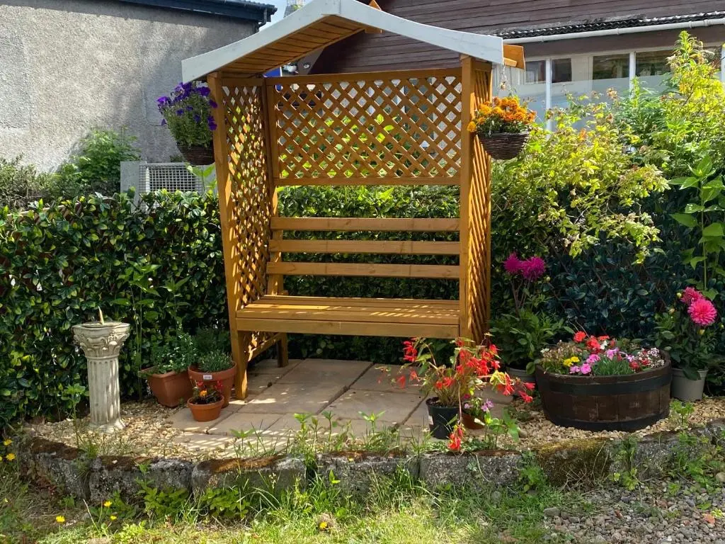 a wooden bench sitting in a garden with flowers at Bosta B&B in Inverness