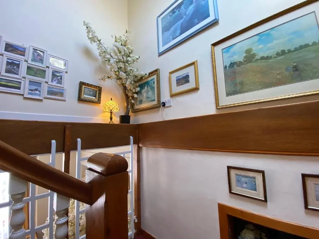 a living room with a staircase and paintings on the wall at Bosta B&B in Inverness
