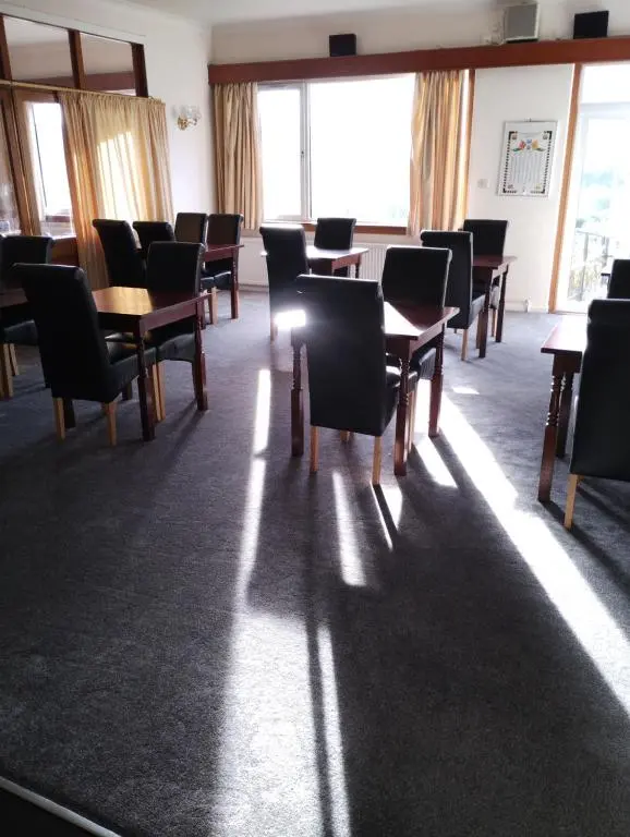 a dining room with tables and chairs and windows at Ravenswood Social Club in Banchory